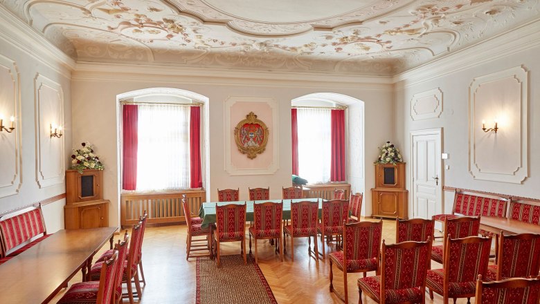 Groß-Siegharts Castle, © Waldviertel Tourismus, lichtstark.com An elegant room in Groß Siegharts Castle with red chairs, a long table and a decorative ceiling.