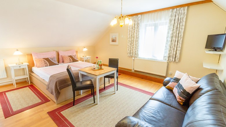 Guest room, © Annemarie Heller Cozy guest room with double bed, sofa, table and chairs, bright furnishings.