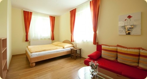 House Schiller Patrizia, © Patrizia Schiller Bright room with double bed, red sofa and curtains.