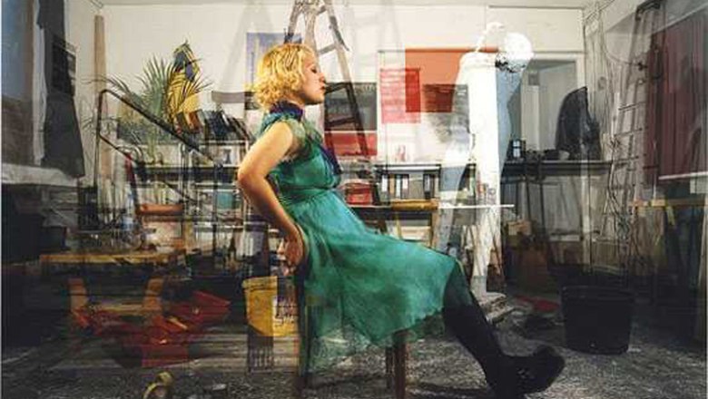 Weinviertel Photo Weeks, © FLUSS / John Hilliard A woman in a green dress sits on a chair in a crowded room.