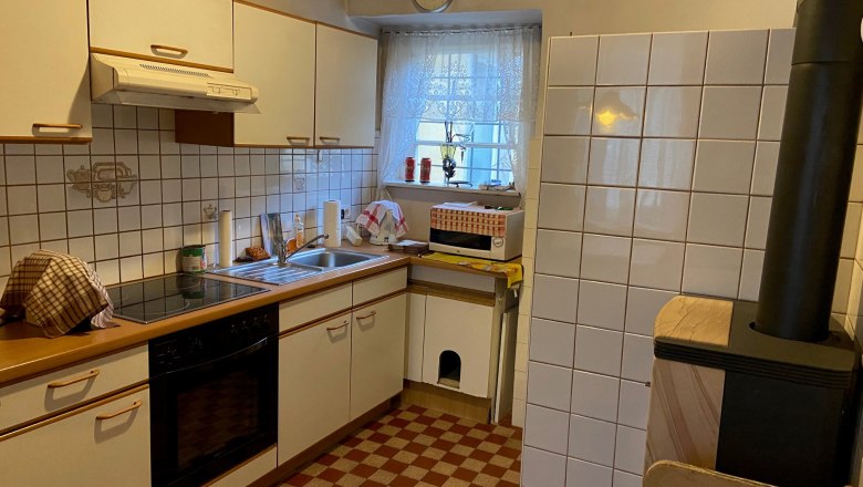Kitchen, © Wiener Alpen Kitchen with white cupboards, stove, sink and wood-burning stove.