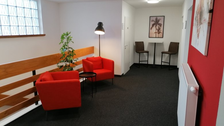 Pension zum Spitz, © Pension zum Spitz Cozy sitting area with red armchairs and floor lamp in a hallway.