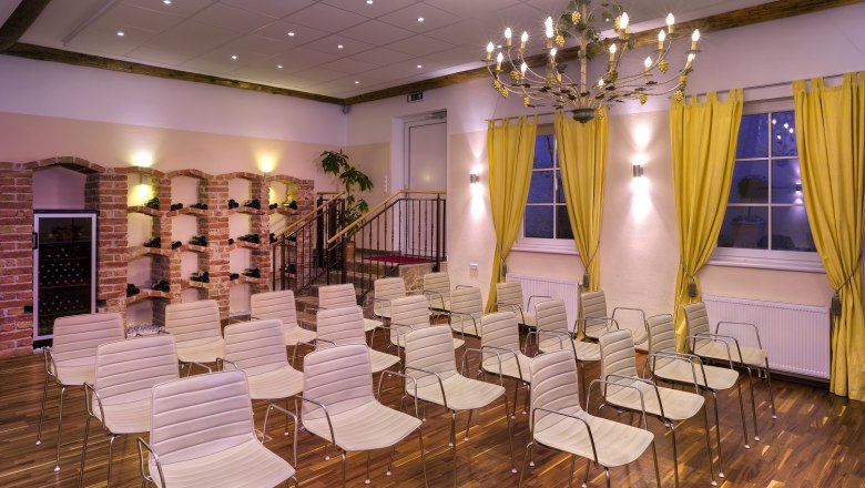 Winzerhotel Gumpoldskirchen, © Winzerhotel Gumpoldskirchen A conference room with white chairs, yellow curtains and a chandelier.