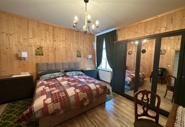 Superior room, © Schloss Gut Ziegersberg Cozy bedroom with wooden walls, double bed, mirrored closet and chandelier.