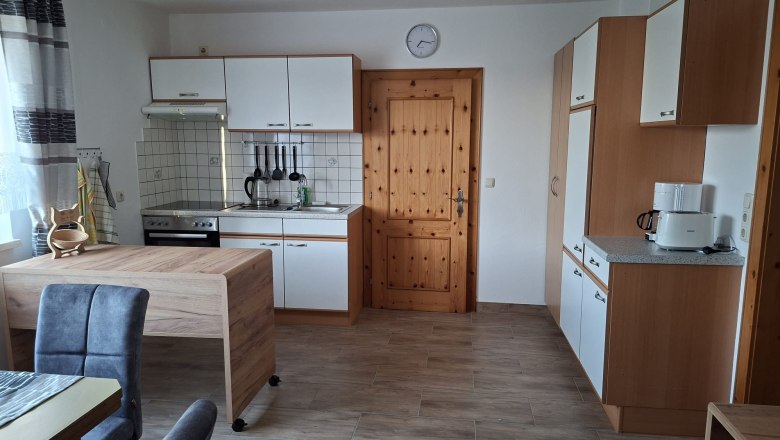 Kitchen, © Ferienwohnung Penz Stolzenthal, Fotograf Hermine Penz Modern kitchen with wooden and white units, dining table, chairs and kitchen appliances.