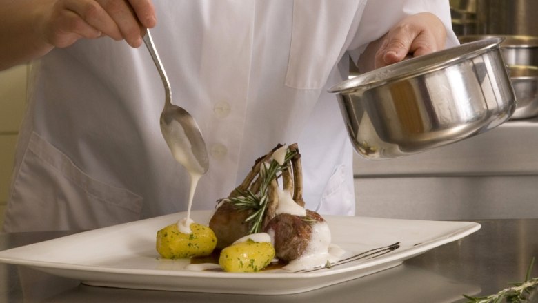 Dining at the Hotel "Wachau", © Hotel"Wachau" A chef prepares a dish of lamb chops and potatoes on a plate.