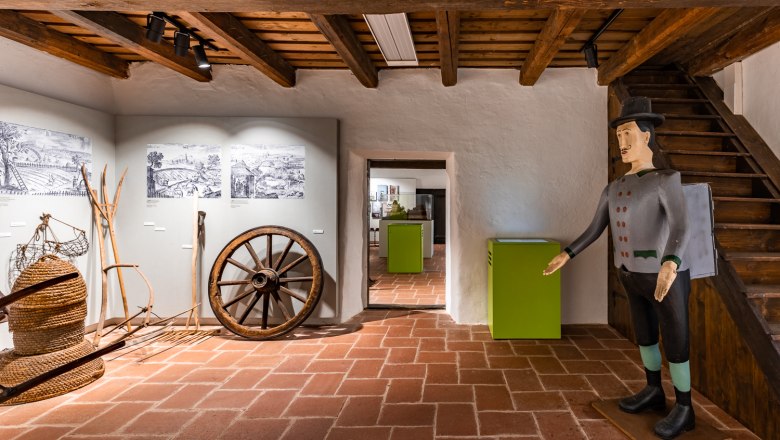Krumbach Museum Village, © Wiener Alpen, Christian Kremsl Interior view of a museum with old agricultural tools and a wooden figure.