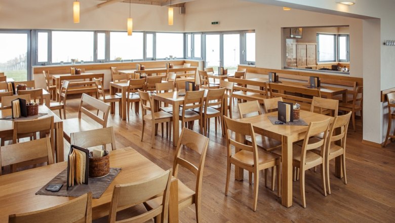 Elegant wine tavern with a feel-good ambience., © Weingut & Weinblick Grafinger Interior view of an elegant wine tavern with wooden furniture and large windows.