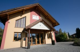 Vinotheque Bouton, © Doris Schwarz König Entrance to the Bouton wine shop with yellow façade and wooden roof.