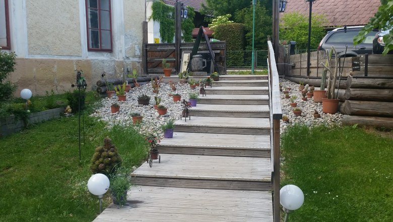 Outdoor area, © Thomas Lutz Wooden staircase next to a church with potted plants and pebbles.