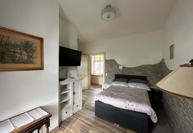 Room single bed, © Schloss Gut Ziegersberg A cozy room with a single bed, a TV on the wall and a small table. Light-colored walls and wooden floors create an inviting atmosphere.