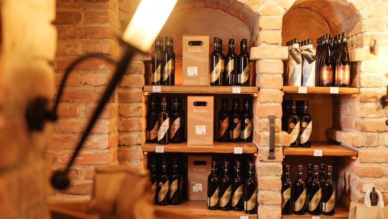 Wine.restaurant Neustifter, © Weinviertel Tourismus / Michael Reidinger Wine bottles in a rustic cellar shelf made of bricks.