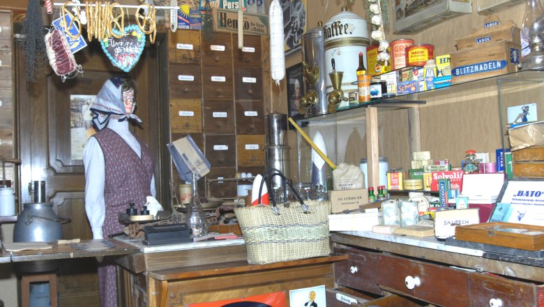 Kaufmann Museum Traiskirchen, © Museum Traiskirchen Interior view of a historic merchant's store with shelves full of old products and a mannequin in traditional clothing.