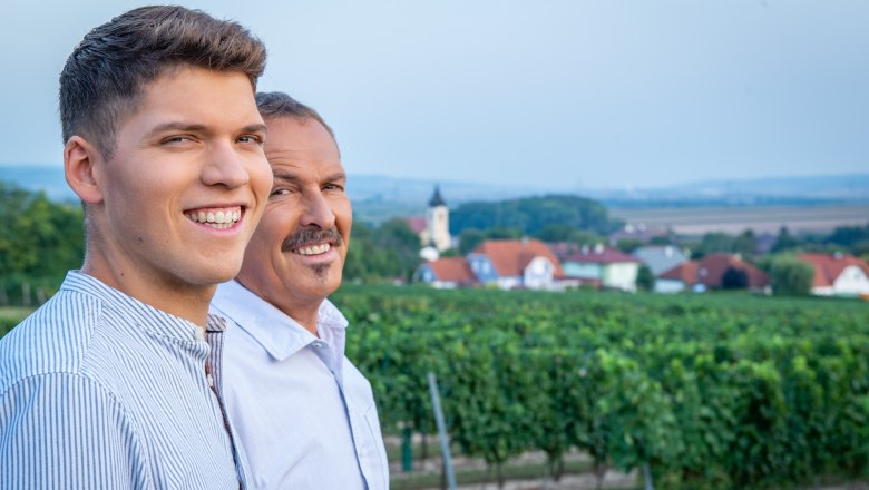David Gutmayer and his father, © Martin Lifka Photography Two men smile in a vineyard with a village in the background.