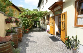 Wine tavern Zierer, © Zierer Entrance of a wine tavern with yellow doors, cobblestones and plants.