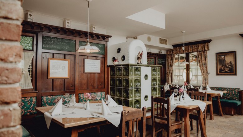 Cozy traditional house at the foot of the Schneeberg, © Niederösterreich Werbung/Rita Newman Cozy restaurant with wooden furniture, tiled stove and decorated tables.
