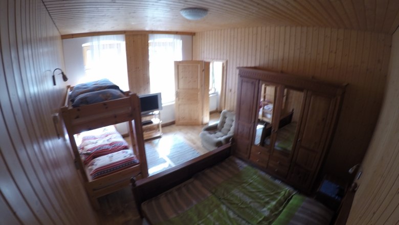 Bedroom vacation apartment 2, © dmgrauszer Wood-paneled bedroom with bunk bed, double bed, closet and TV.