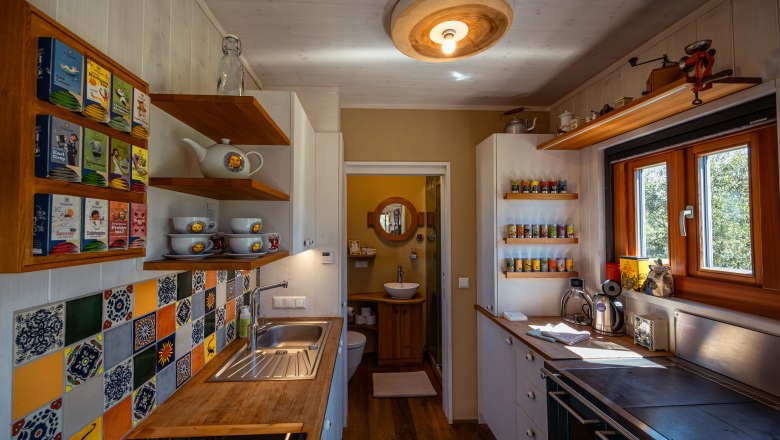 SONNENTOR country lofts, © Niederösterreich Werbung / Maximilian Pawlikowsky Small, cozy kitchen with wooden furniture, colorful tiles and spice racks.