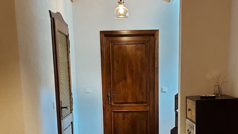 Anteroom, © Bernadette Gierlinger A hallway with wooden doors, wooden ceiling and modern lamps.