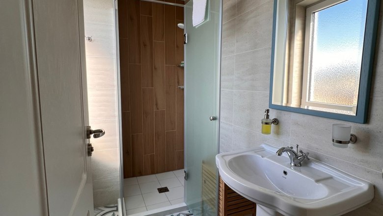 Bathroom, © Mediterraneo Ybbs Modern bathroom with patterned tiled floor, washbasin, mirror and shower with glass wall.