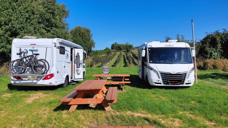 Bachleiten Platzl, © Winzerhof Ernst Two mobile homes are parked on a meadow next to a picnic table, with vines in the background.