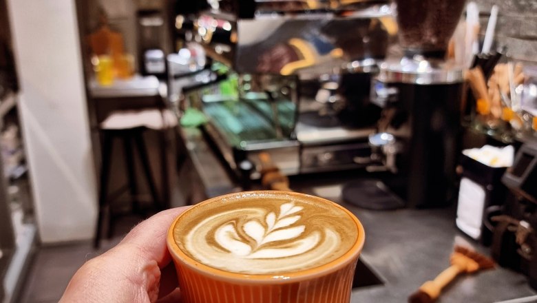 TDR Egon to go coffee cup, © Yana Tereshchenko Espresso with milk foam held in the hand in the background of the counter