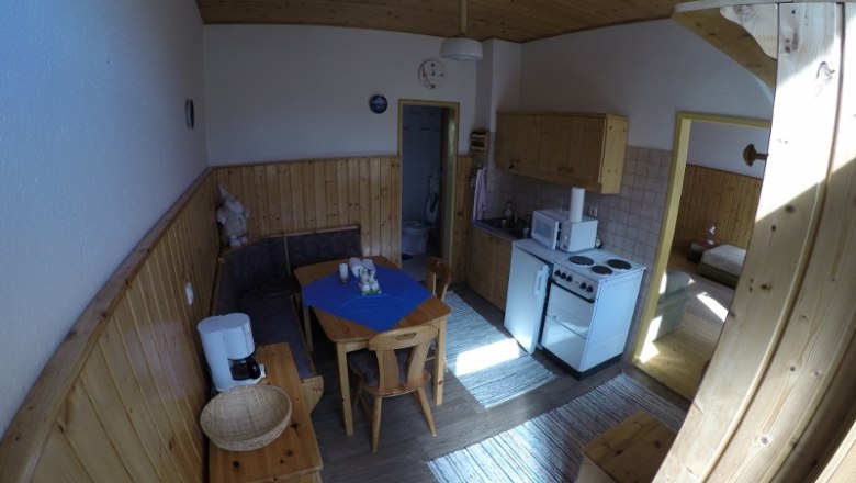 Kitchen/living room apartment 1, © dmgrauszer Kitchen-living room in a vacation apartment with wooden furniture, dining table, kitchenette and access to a bedroom.
