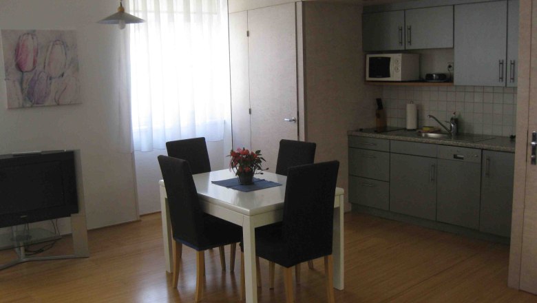 Kitchen, Apartment Gutmann, © Gutmann Gray kitchenette with dining table and blue chairs.