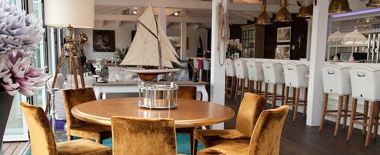 Bar area, © Diamond Club Atzenbrugg Elegant bar area with round wooden tables, velvety chairs and a bar with white stools.
