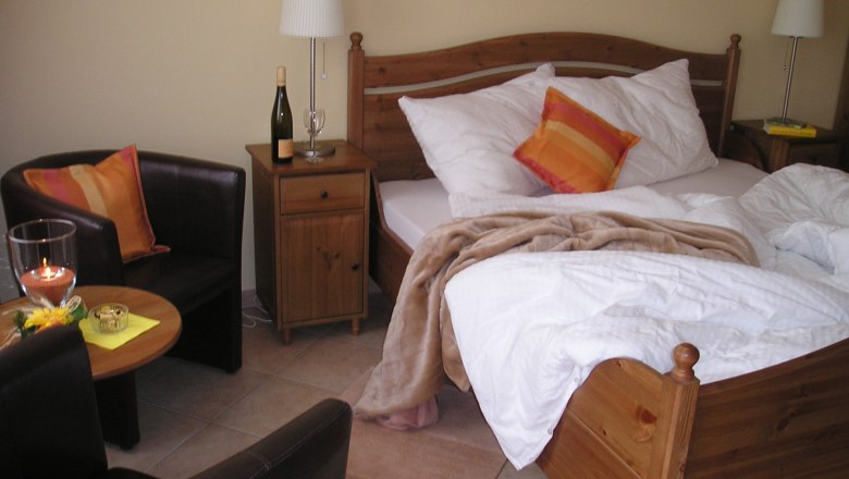 Guest room, © Familie Lachmayer Cozy guest room with double bed, bedside table, lamp, armchair and table.