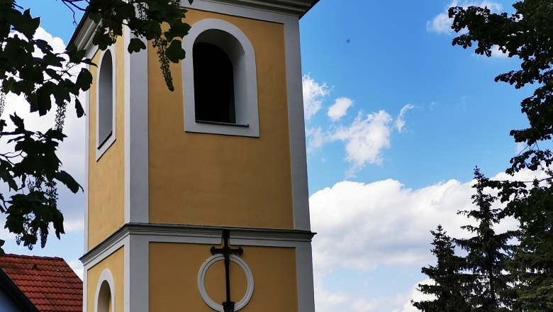 Ragelsdorf bell tower, © Weinstraße Weinviertel Bell tower in Ragelsdorf against a blue sky and trees.