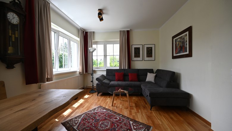 Living room, © Christine Kuppelwieser Modern living room with gray sofa, wooden table, carpet and wall clocks.