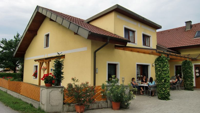 Vacation apartments & private rooms Leeb, © eigene Yellow house with terrace and people sitting outside.