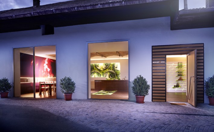 Kohl Winery, © Weingut Kohl Exterior view of a modern winery with illuminated windows and plants.