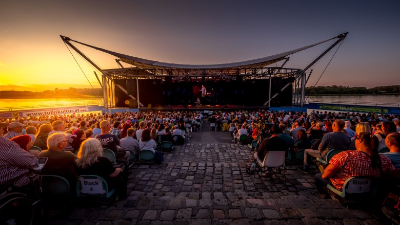 TDR- Donaubühne Tulln, © Hans Eder Open-air stage on the Danube at sunset with an audience.