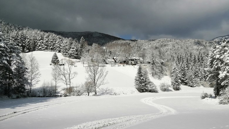 Oberhof country estate in winter, © Landsitz Oberhof Snow-covered landscape with forest and hills, dark clouds in the sky.