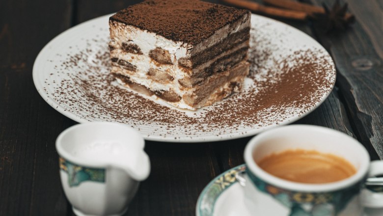 Homemade pastries, © cervodoro A plate with a slice of tiramisu, a cup of coffee and a milk jug next to it on a wooden table.