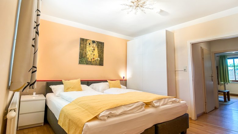 House Morgensonne Bedroom II, © Fam. Pauker Bedroom with double bed, yellow bed linen and artwork on the wall.