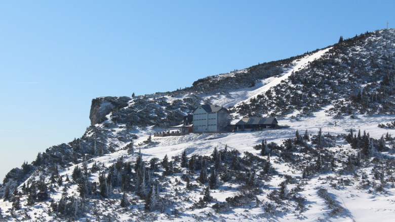Ottohaus in winter, © Scharfegger´s Raxalpen Resort Winter landscape with the Ottohaus on a snow-covered mountain under a clear sky.