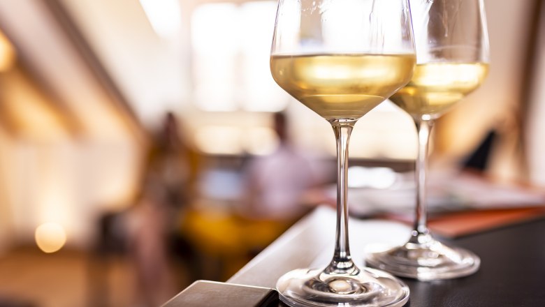 Enjoy the wine, © Weinviertel Tourismus GmbH / Herbst Two glasses of white wine on a table, blurred background.