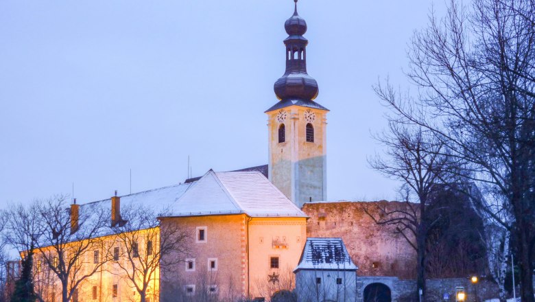 postcard (39) © Municipality of Gloggnitz, photographer Johannes Hartl, © Stadtgemeinde Gloggnitz, Fotograf Johannes Hartl Gloggnitz Castle in winter with illuminated tower and snow-covered roof.