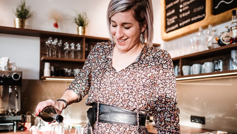Cafe Herzstück, © Cafe Herzstück_Stephanie Kirschner Woman in flowered dress pouring drink in a café.