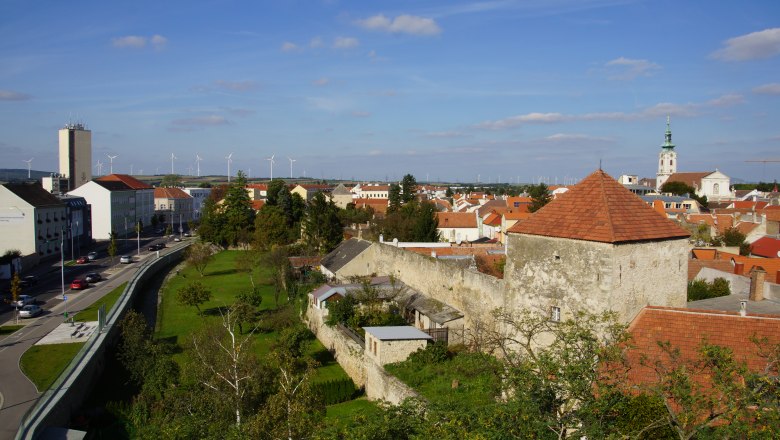 City moat Bruck an der Leitha, © Erwin Huber Town view of Bruck an der Leitha with town wall, church and wind turbines in the background.