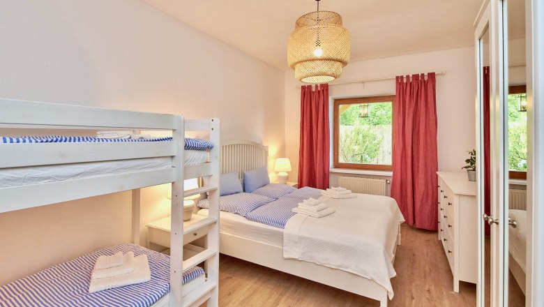 Top 1 - Bedroom, © VP FeWo OG Bedroom with bunk bed, double bed, red curtain and wooden floor.