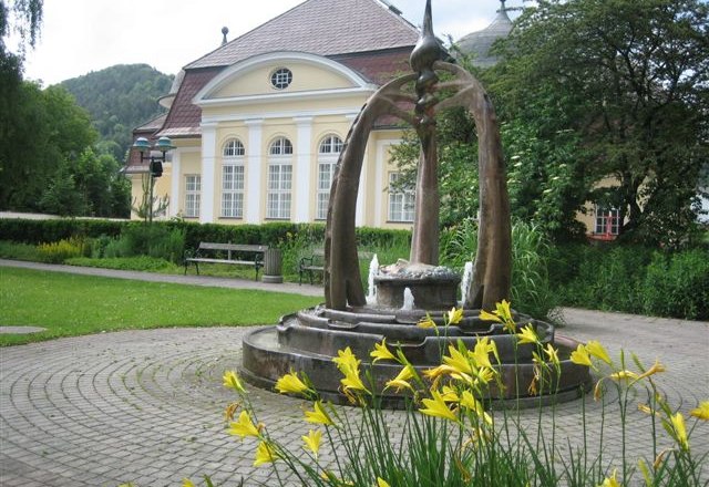 Pernitz, parish hall, © Marktgemeinde Pernitz, Foto privat Fountain in front of a historic building with yellow flowers in the foreground.