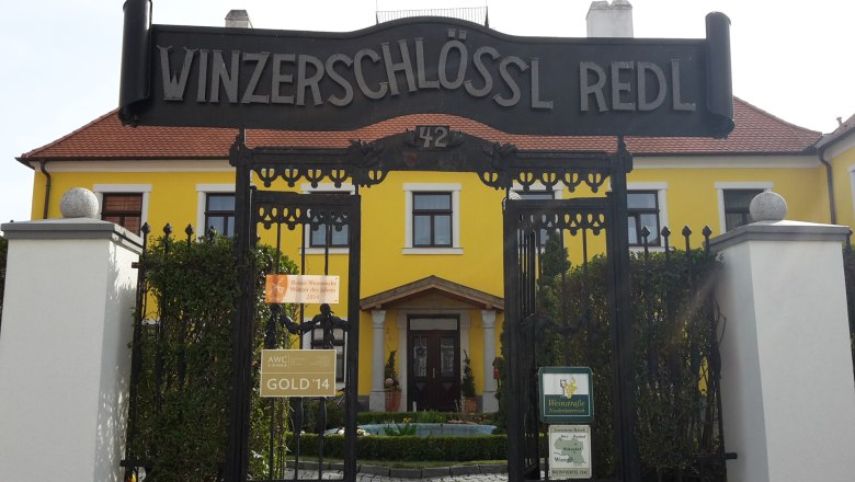Winzerschlössl, © Weingut Redl Entrance gate to Winzerschlössl Redl with yellow building in the background.