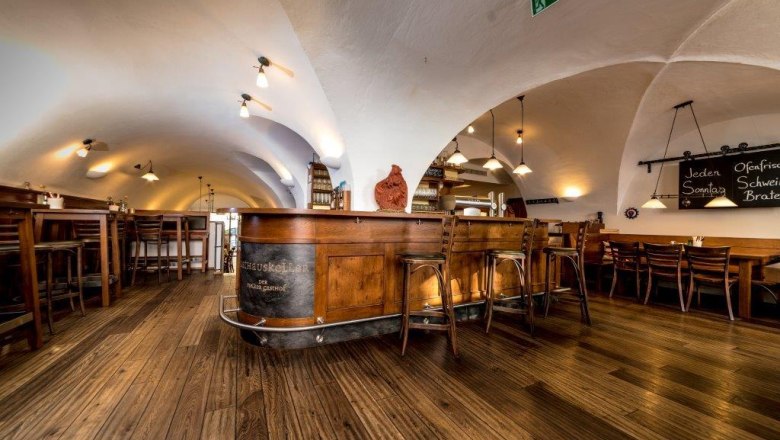 RHK Schank, © Lorenz Wachau Interior view of a rustic dining room with wooden floor and vaulted ceiling.