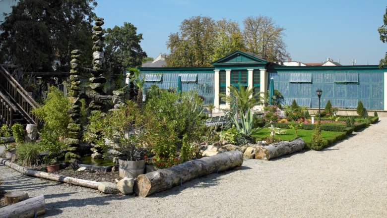 Nature in the garden, © Natur im Garten/Alexander Haiden A well-tended garden with plants, a gravel path and a greenhouse in the background.
