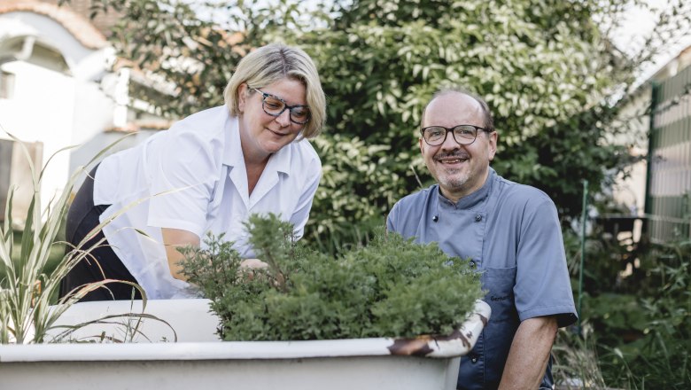 Hosts Gerhard and Isabella Bauer, © Niederösterreich Werbung/David Schreiber Two people gardening in an old outdoor bathtub.
