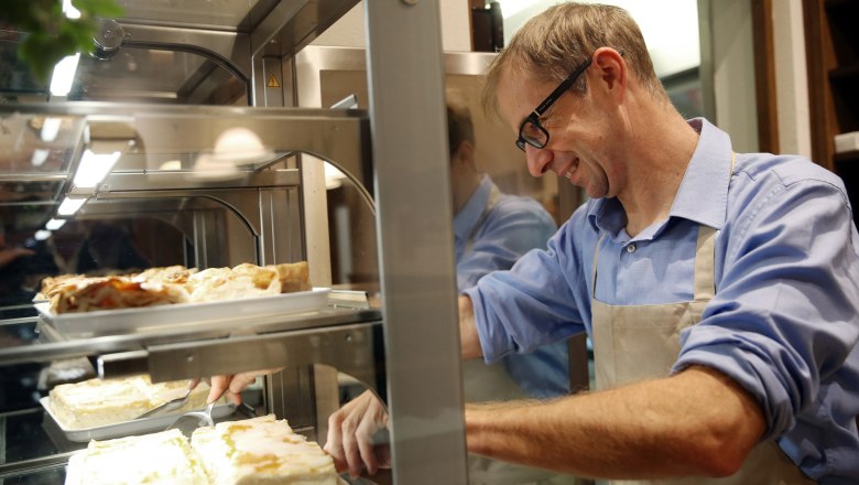 In the kitchen at Waldgasthof Steinbründl, © Familie Kogler-Renner A man in a kitchen cuts cakes in a display case.